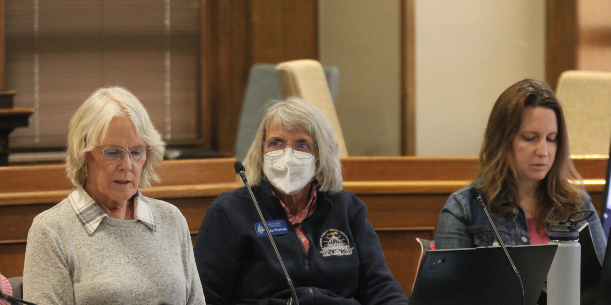 Three woman sitting at in a row at a table with microphones.