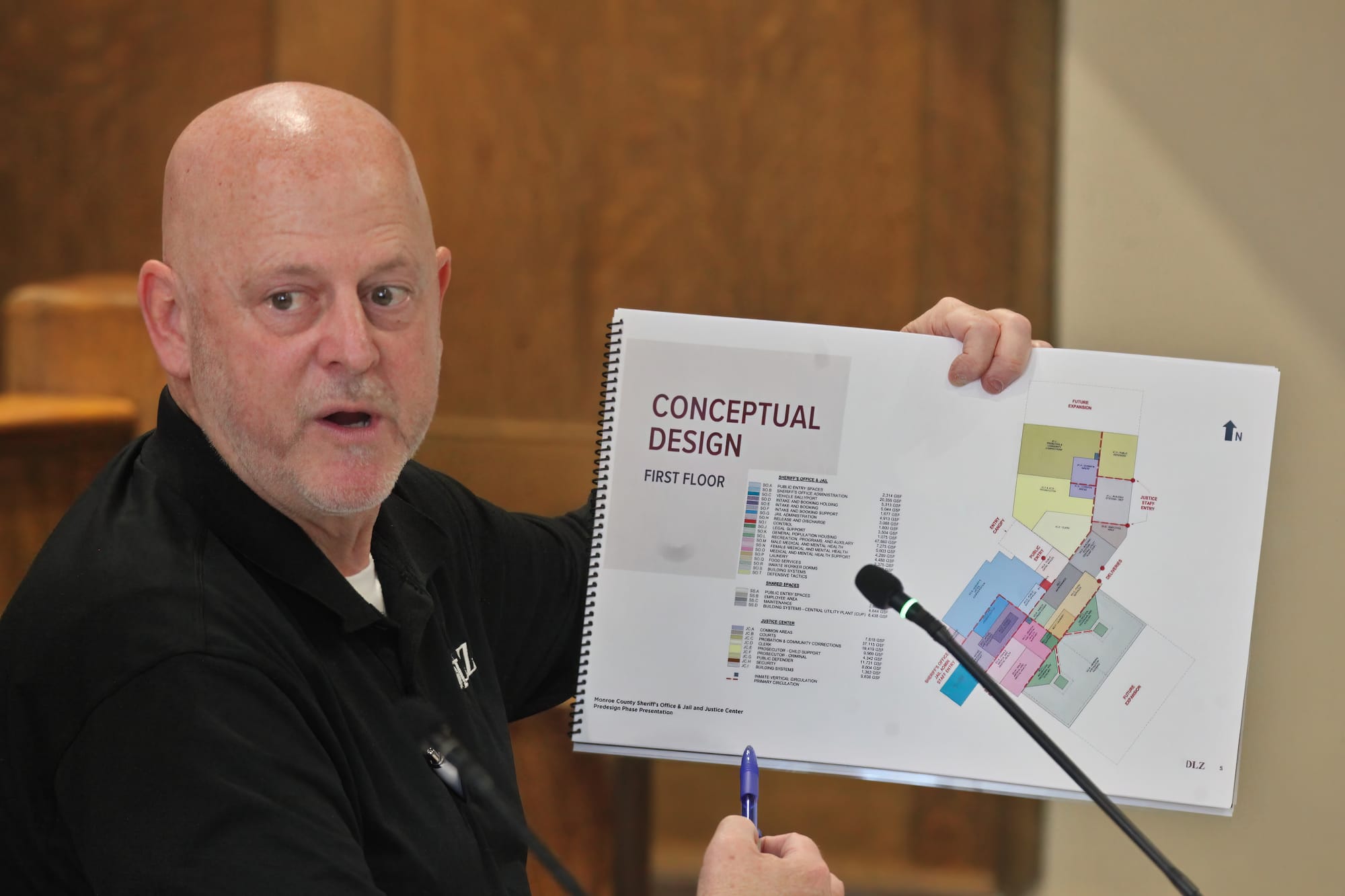 A man holds up a conceptual design layout and points to it.