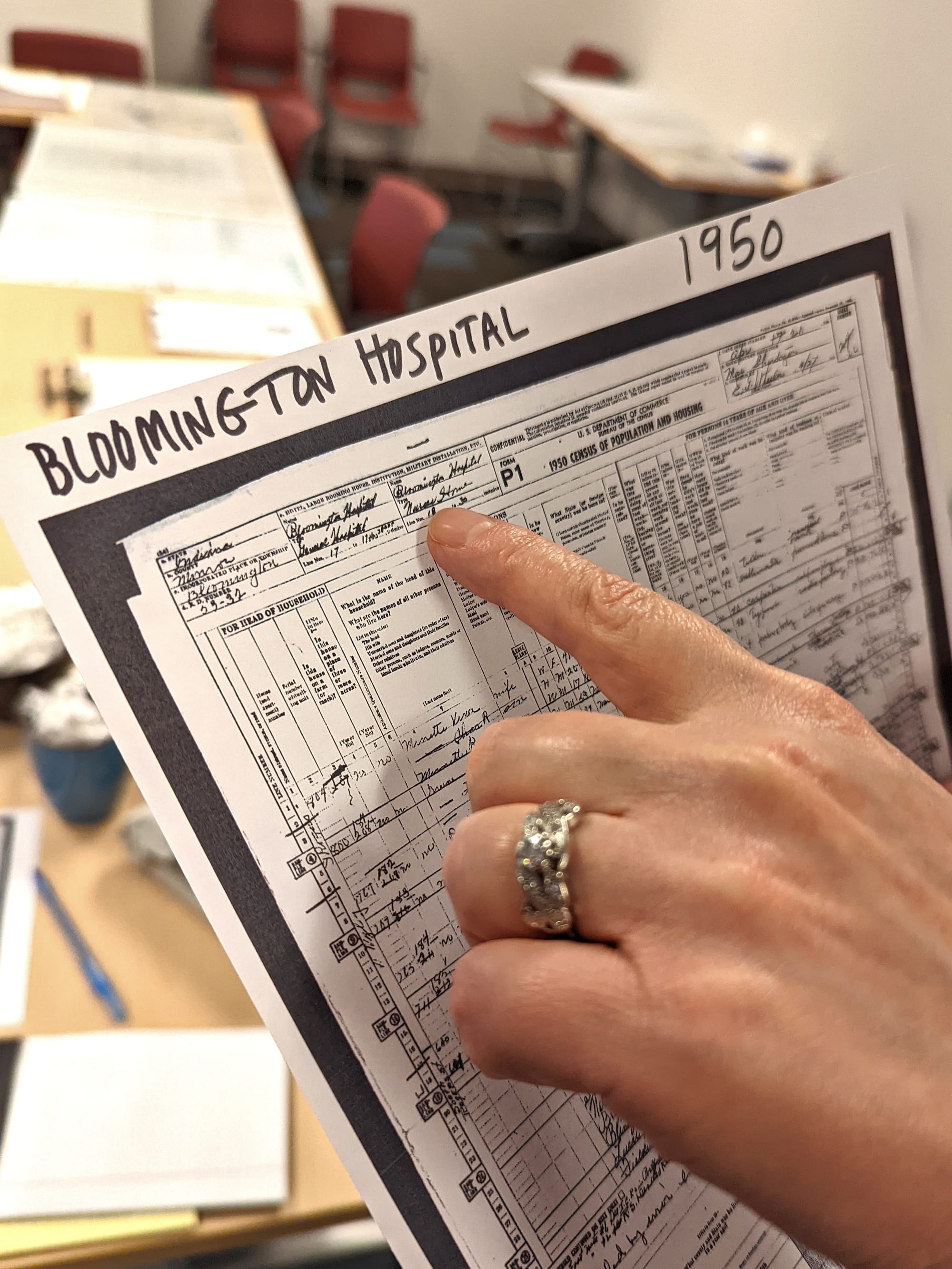 close up of hand with finger pointing at a printout of Bloomington Hospital nurses residences in 1950 handwritten census