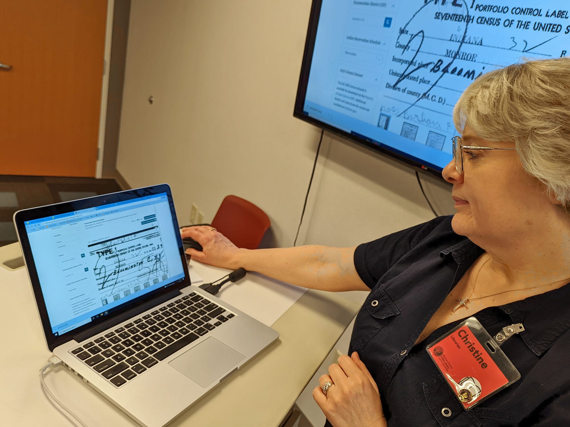 woman standing at a desk with laptop computer showing 1950 census entries