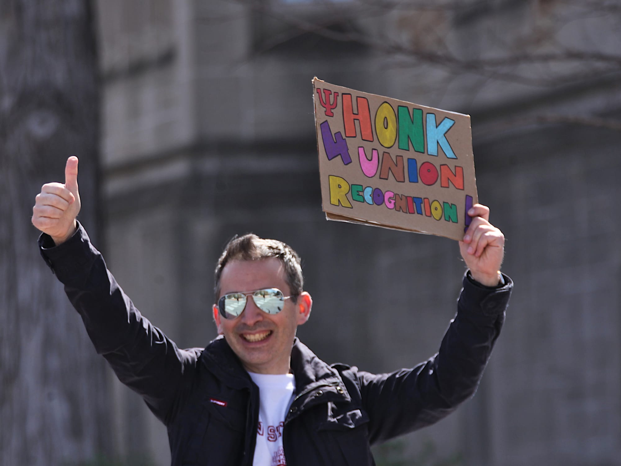 Isolated shot of man holding cardboard sign with hand-lettered sign that says, "Honk 4 union recognition."