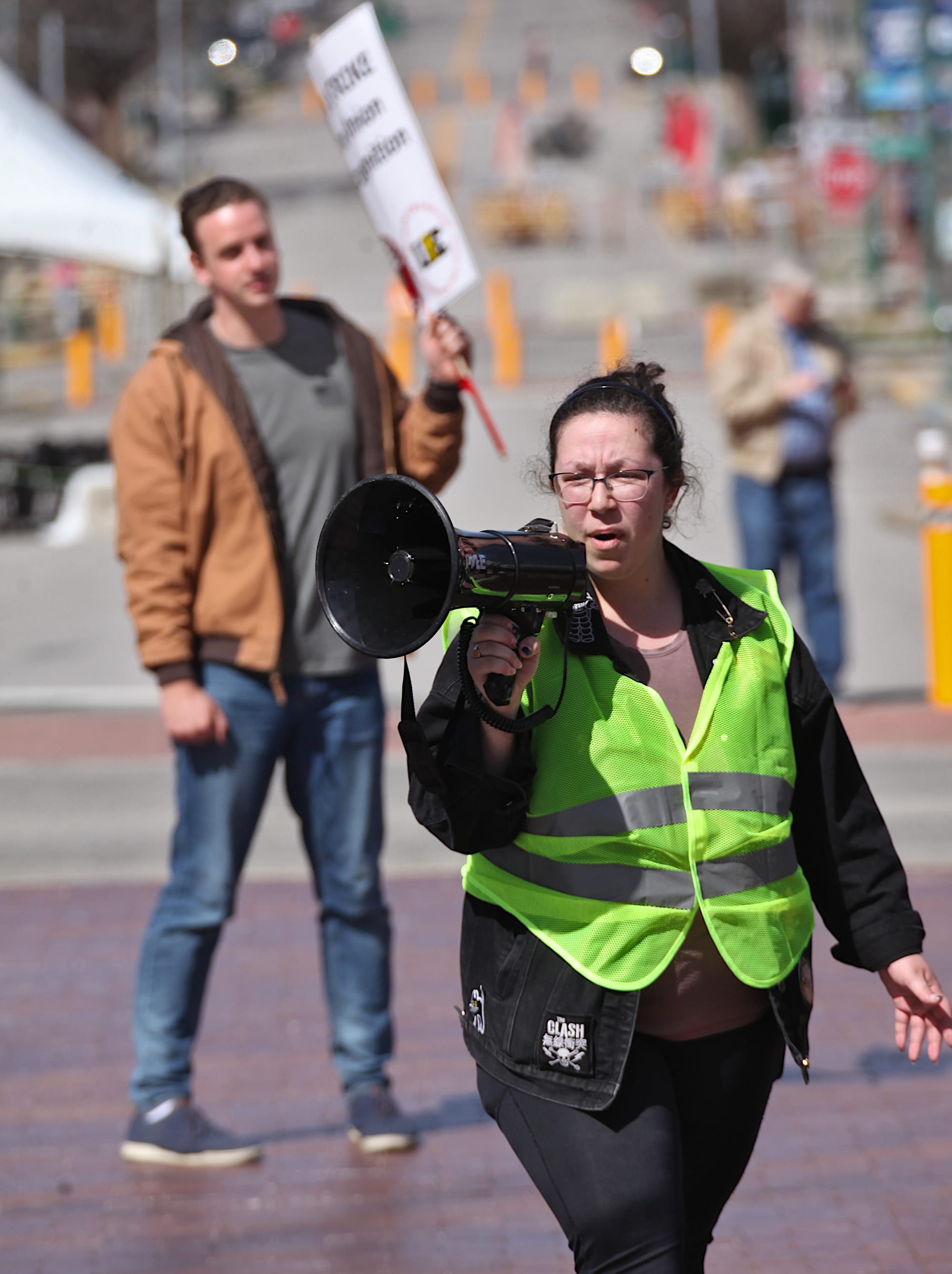 Woman in yellow reflective vest holding a megaphone.